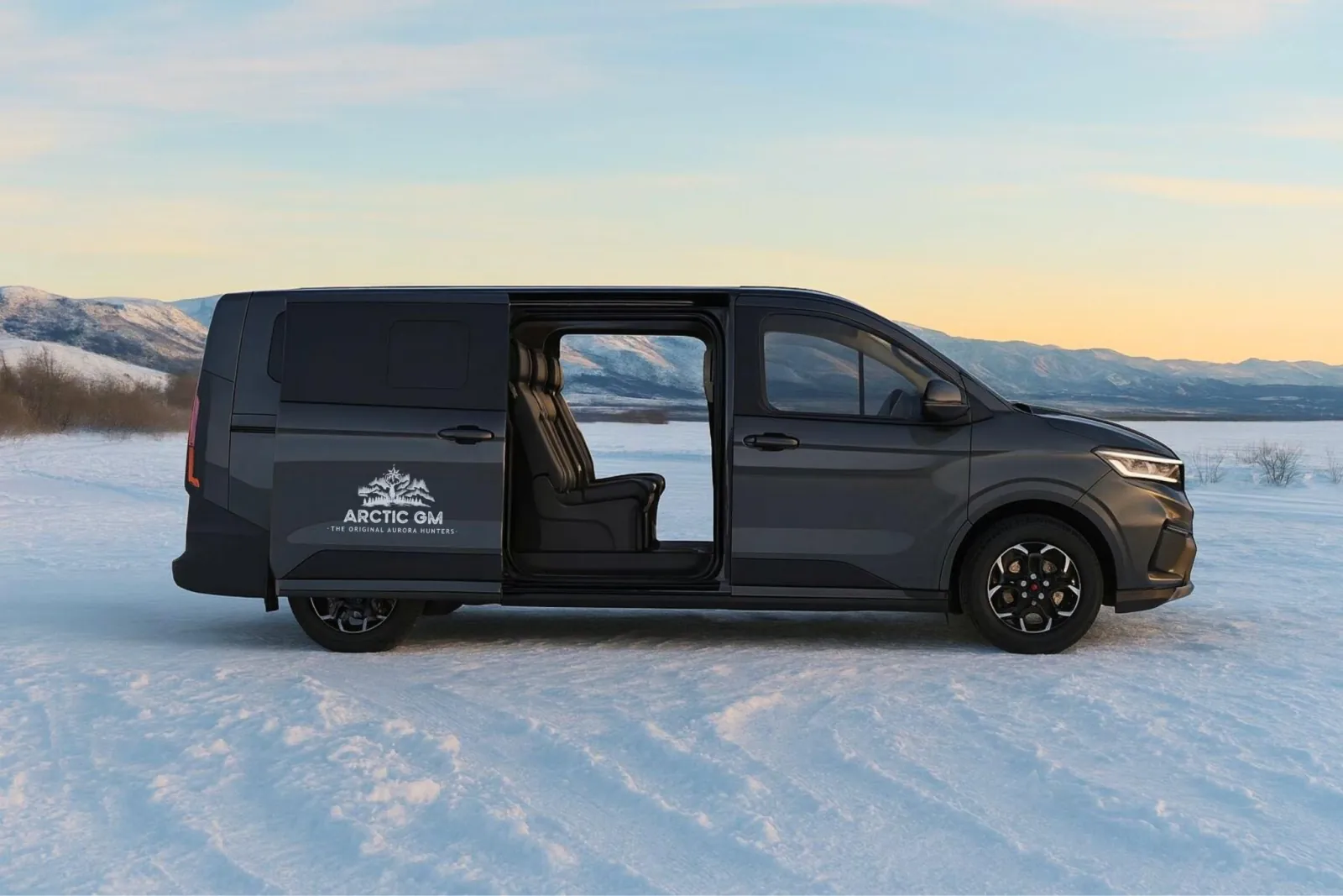 A dark Arctic GM van with its sliding door open, parked on snow at dusk
